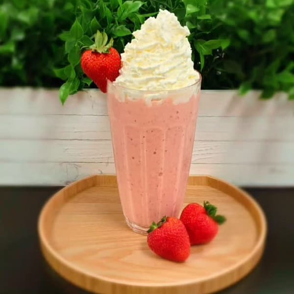 Strawberry smoothie with whipped cream and fresh strawberries on a wooden tray at Vigo Coffee.